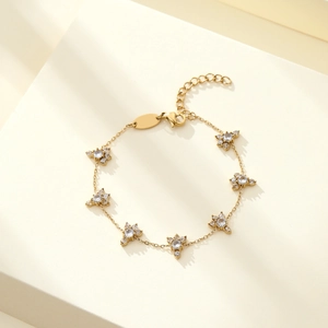 Detailed macro view of golden flower charms with white zircons on a steel chain
