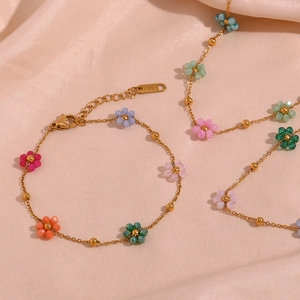 Colorful beaded flower necklace and bracelet set in gold finish on pink silk background