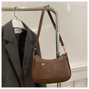 Detailed macro view of vintage brown leather shoulder bag with a metal buckle pocket