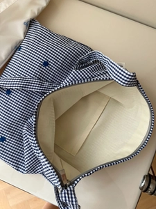 Vue macro de l'intérieur du sac en toile à carreaux bleus avec broderie et fermeture