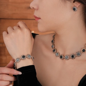 Close-up of elegant flower-shaped gold necklace and bracelet set with navy stones