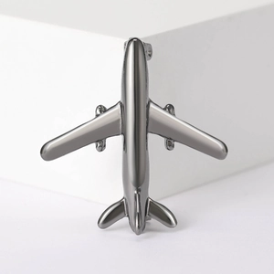 Macro detail of minimalist silver airplane brooch with a polished metallic finish