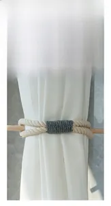 Detail of Nordic bow curtain tieback showing polished wood stick and beige woven rope