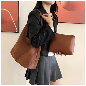 Close-up of brown suede tote bag set with matching smooth leather clutch shown on a model