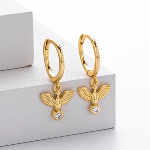 Detailed view of gold bird earrings with sparkling round zircon on a white stand