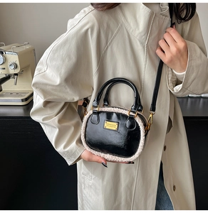 Detail of a chic black leather handbag with white faux fur trim and gold metal accents