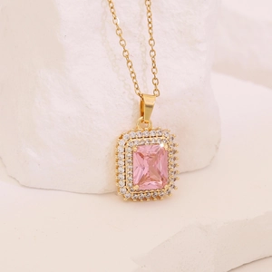 Pink zircon flower pendant on a gold geometric necklace over white natural stone