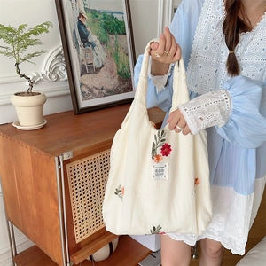Close-up of elegant floral embroidery and woven label on a white canvas tote bag