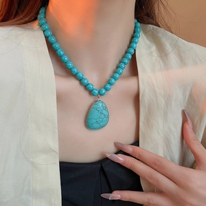 Close-up of bohemian turquoise beaded necklace with cracked water drop pendant on a model