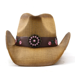Detail of western straw cowboy hat featuring pink floral embroidery and vintage bronze badge