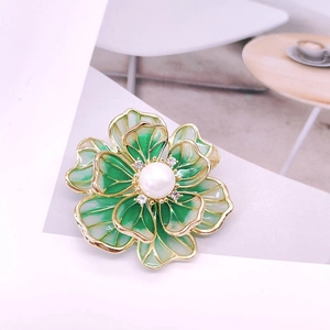 Detail of enamel flower brooch with green petals, a white pearl center and gold framing