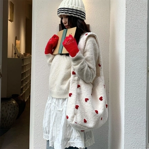 Dettaglio della borsa tote in peluche con ricami a cuore rosso e guanti a maglia