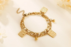 Macro detail of gold double-layer chain bracelet featuring square poker card charms