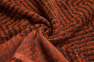 Macro shot of thick herringbone weave fabric in orange and brown for winter ponchos
