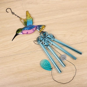 Close-up of colorful hummingbird wind chime with blue metal tubes on wooden floor