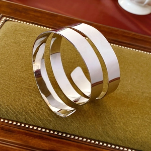 Polished silver multi-layer metal arm cuff bracelet on a vintage green velvet display