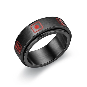 Macro detail of black matte spinner ring with red dice pattern and brushed metal texture