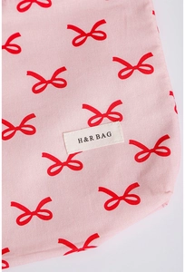 Detailed macro view of pink cotton fabric with red bow patterns and sewn brand label