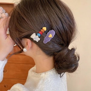 Detail of cute flocked bear and colorful heart hair clips worn on side of hair