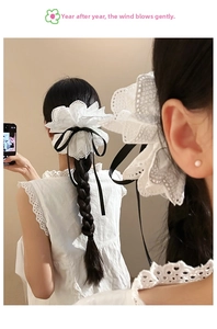 Détail d'une pince à cheveux fleur en dentelle blanche avec ruban noir sur une coiffure