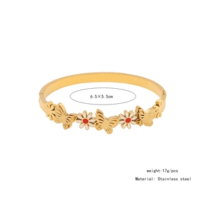 Detail of gold stainless steel open bangle with butterfly and daisy floral motifs