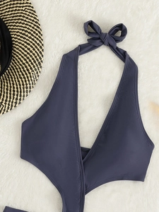 Détail du haut de bikini licou gris foncé avec col en V et gros nœud sur tapis doux