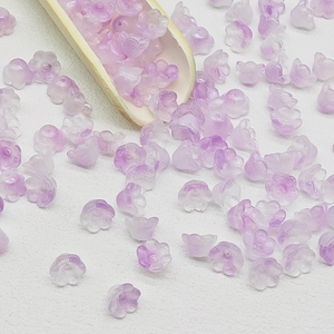 Close-up of translucent purple lily of the valley beads with a wooden tool