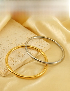 Detail of 18K gold plated stainless steel bangles with hidden clasp on silk background