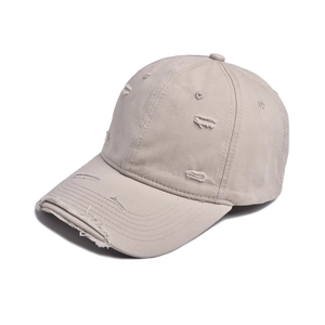 Close-up detail of distressed beige cotton baseball cap with vintage frayed hole design