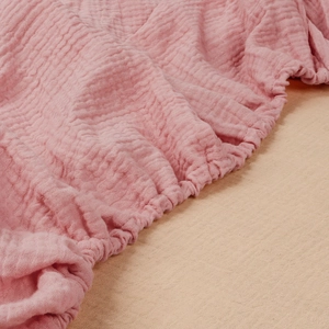 Close-up of pink double muslin cotton bassinet sheet with elasticated hem details