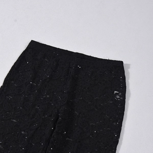 Detalle de pantalones de encaje negro con lentejuelas brillantes en fondo gris