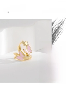 Close-up of pink enamel butterfly hoop earrings with gold plating on marble