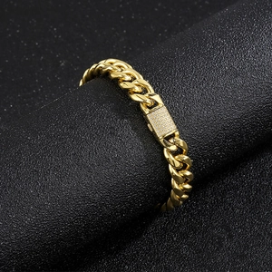 Macro shot of 10mm gold Cuban chain with iced-out CNC diamond clasp on black background