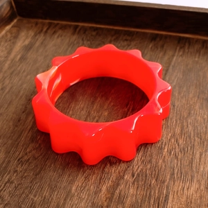 Vue détaillée d'un bracelet en résine acrylique orange avec un design ondulé rétro unique