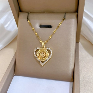 Detail of gold heart pendant with 3D rose and zircon stones on a gold chain