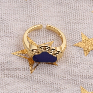 Macro shot of blue enamel cloud charm and golden adjustable band on textured fabric