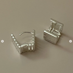 Detailed view of sterling silver square earrings with geometric horizontal textures