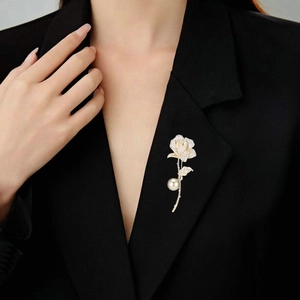 Detail of rose-shaped brooch with cubic zirconia and pearl on a black suit lapel