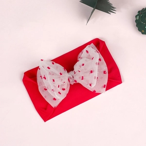 Detail of red elastic baby headband with large white mesh bow for Christmas style