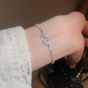 Detail shot of sparkling silver zircon bracelet with star and heart charms on wrist