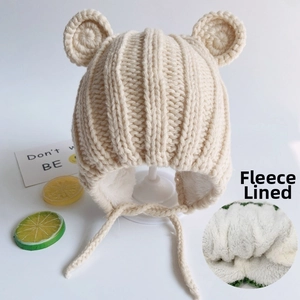 Close-up of cream knit baby hat showing thick white fleece lining and bear ear design