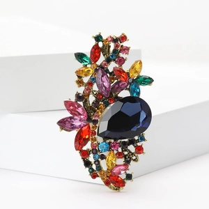 Detailed close-up of vintage floral brooch with colorful crystals and blue teardrop gem