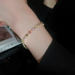 Detailed view of gold plated bracelet with colorful round zircons on a female wrist