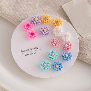 Detailed view of colorful floral resin stud earrings on a white jewelry display card