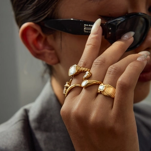 Golden titanium steel ring set with zircon stones on model wearing a grey blazer