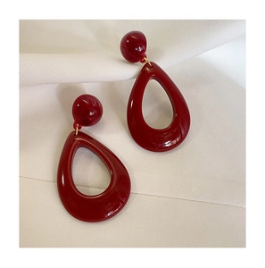 Detailed macro shot of vintage burgundy resin teardrop earrings on elegant fabric