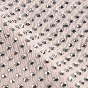 Détail macro de strass argentés sur maille beige pour une robe de soirée scintillante