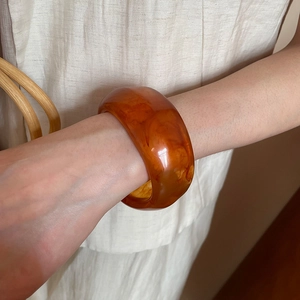 French style gold-plated round bangle featuring amber resin patterns on a model's wrist