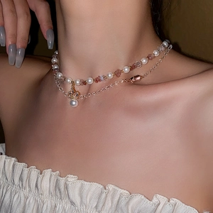 Detail view of double-layer necklace with pearls, pink beads and cross pendant