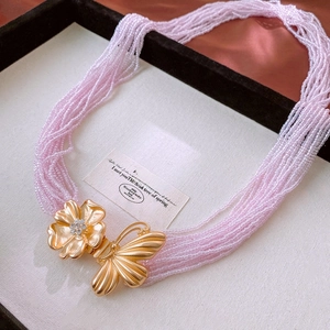 Détail d'une chaîne de taille en perles roses avec fermoir papillon fleuri serti